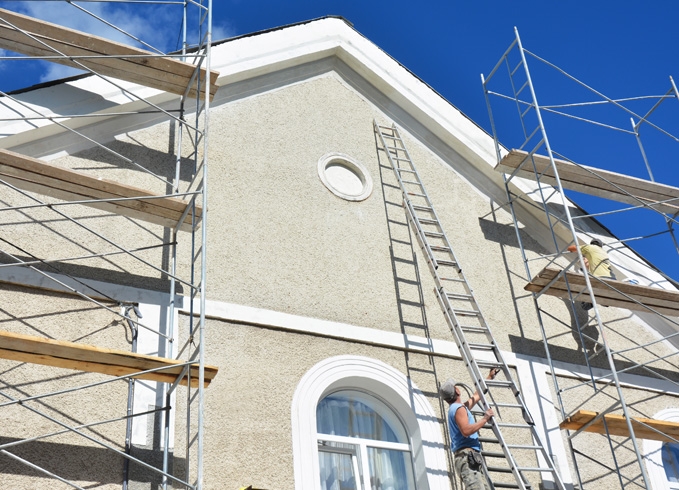 A roofer and a customer talking outside of a house.