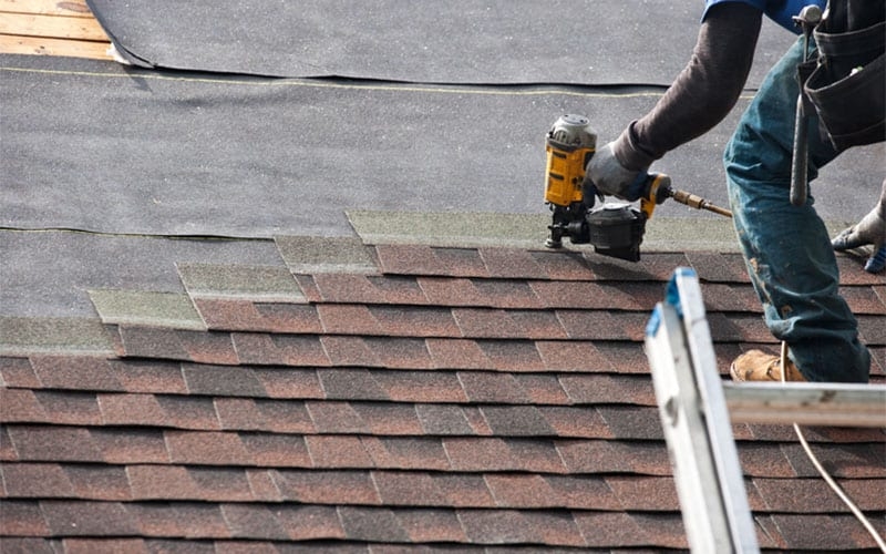 A roofer and a customer talking outside of a house.