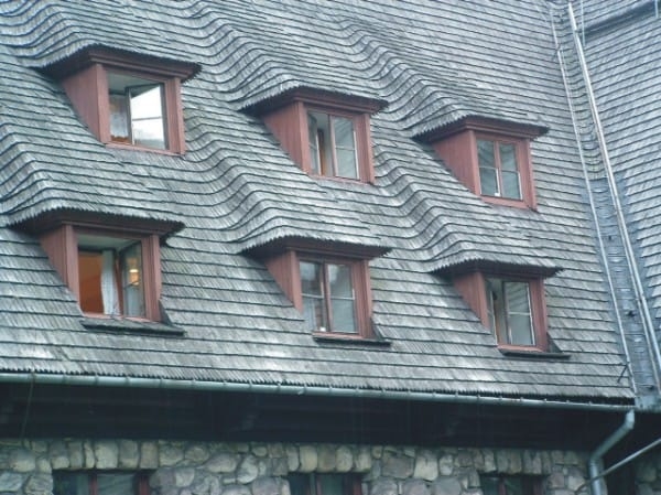 A roofer and a customer talking outside of a house.