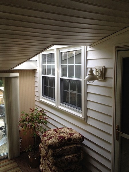 A roofer and a customer talking outside of a house.