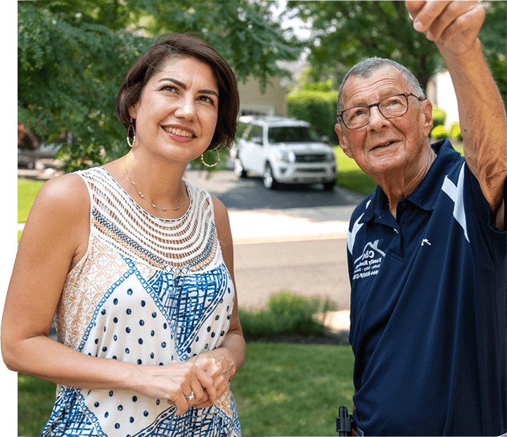A roofer and a customer talking outside of a house.