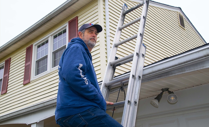 A roofer and a customer talking outside of a house.