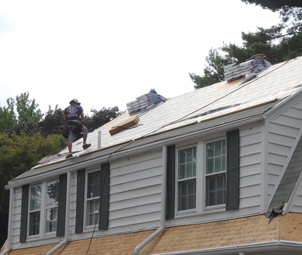 A roofer and a customer talking outside of a house.