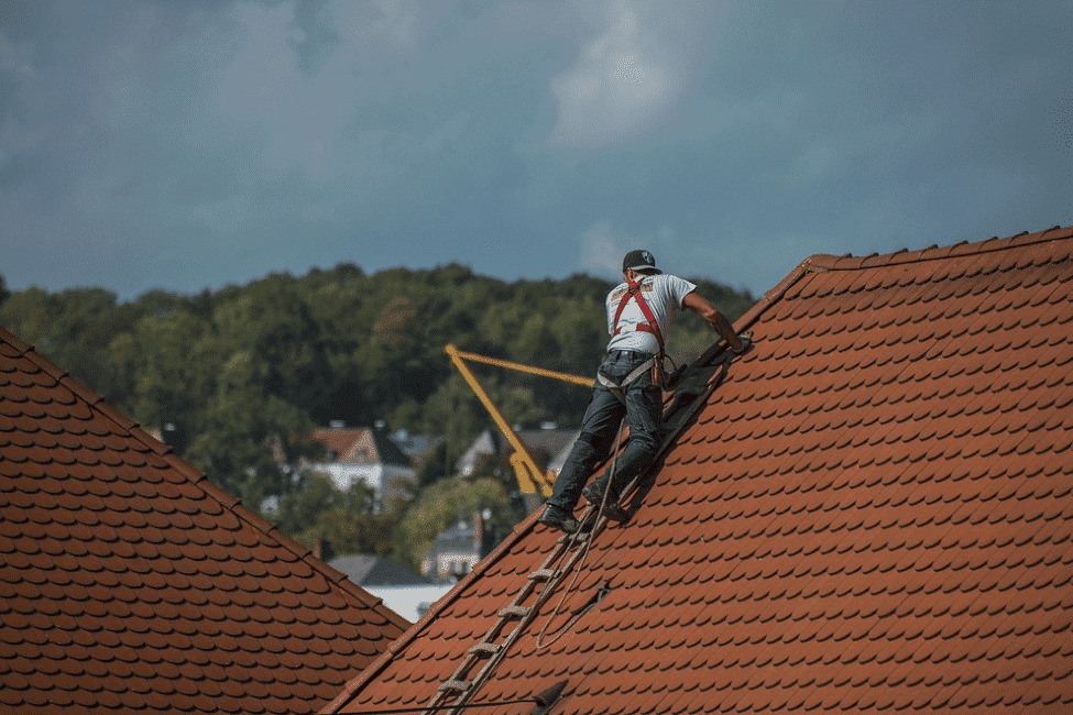A roofer and a customer talking outside of a house.