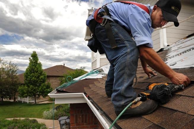 A roofer and a customer talking outside of a house.